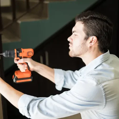 profile-view-attractive-handyman-using-power-drill-fix-door-knob-house-1